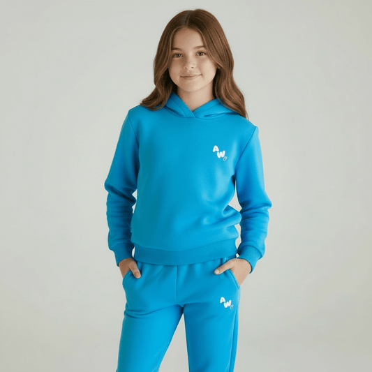 Girl wearing a blue hoodie and pants set with a logo on a gray background