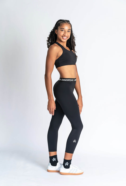 Person wearing black leggings with a visible brand logo on a white background