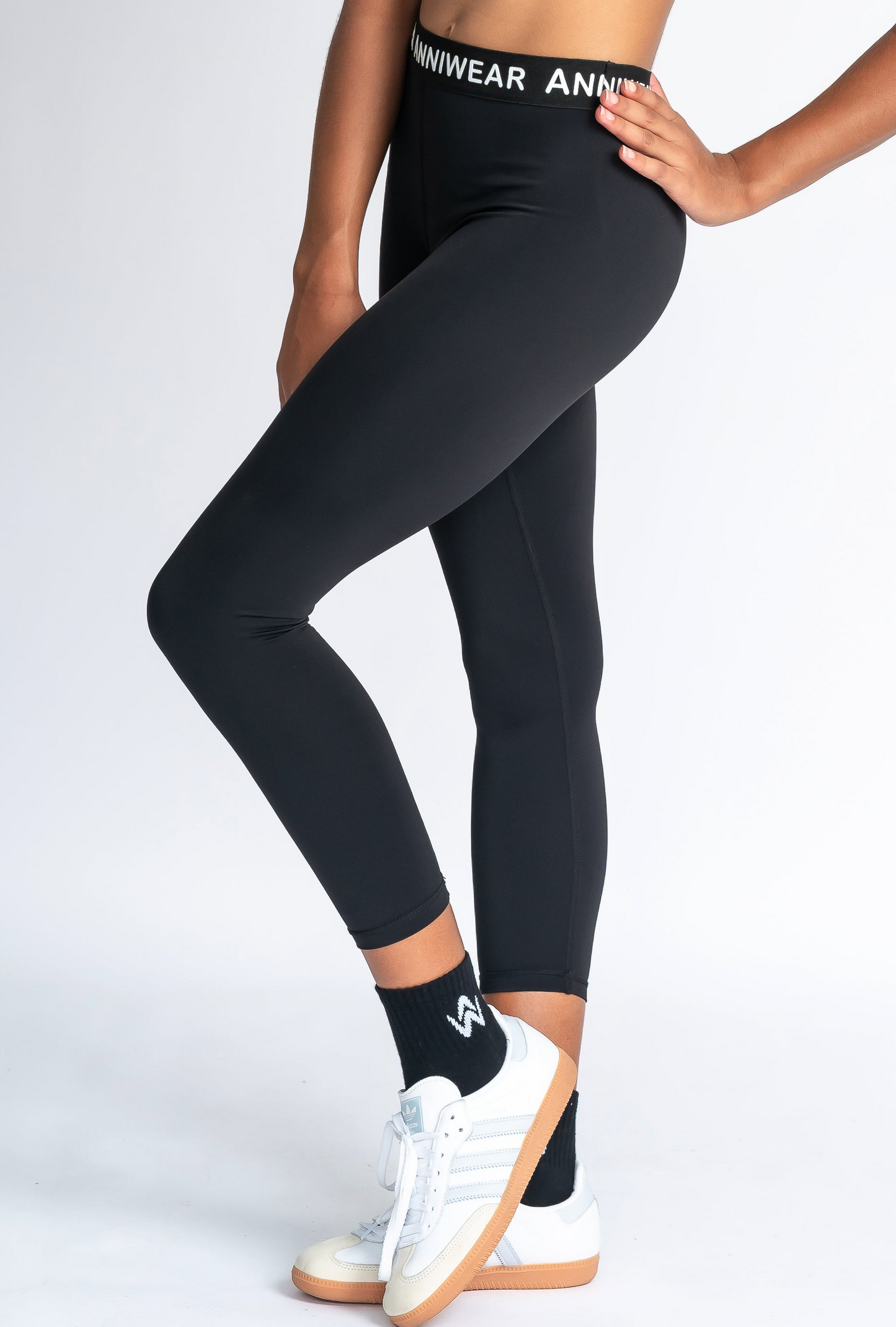 Person wearing black leggings with a visible brand logo on a white background