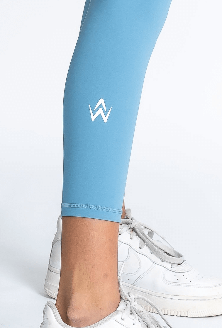 Light blue leggings with a logo worn by a person on a white background
