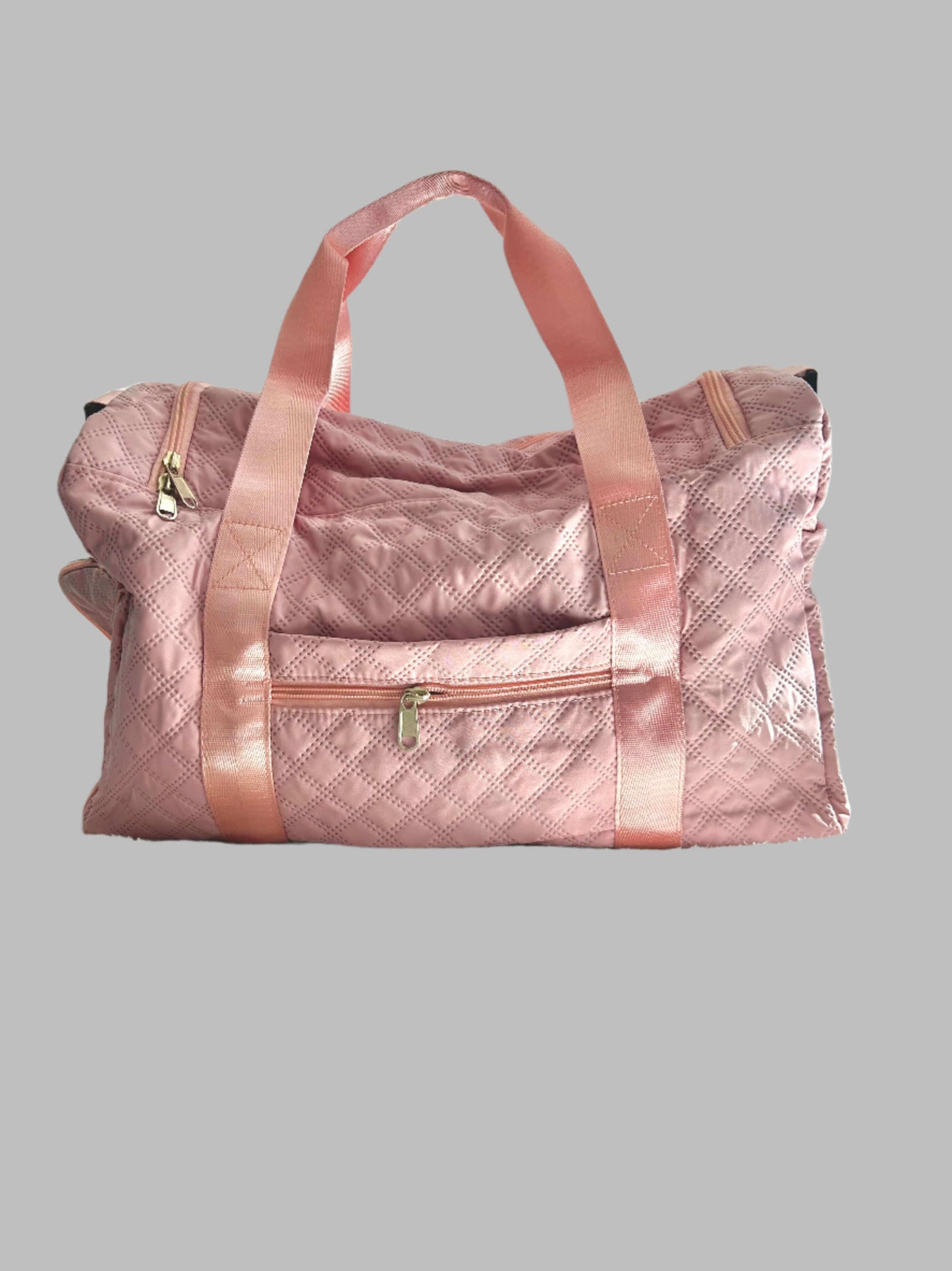 Pink quilted duffel bag on a bed with a white headboard