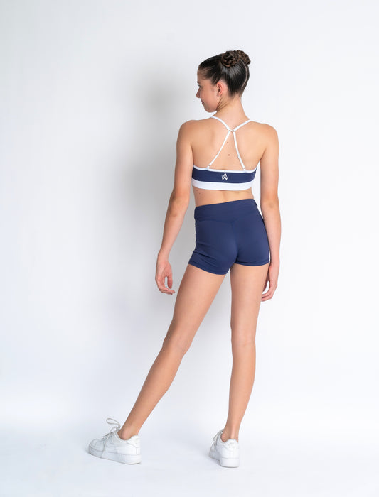 Navy blue & white sports crop and navy blue high-waisted shorts on a plain background