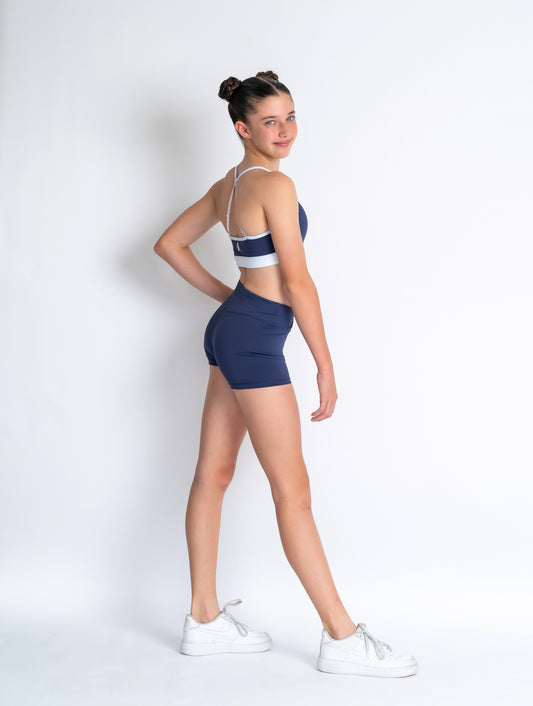 Navy and white sports bra and Navy shorts with a logo on a plain background