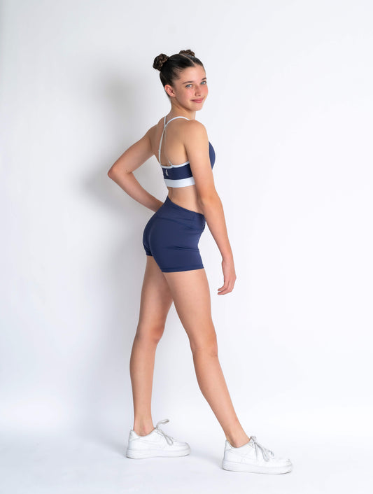 Navy and white sports bra and Navy shorts with a logo on a plain background