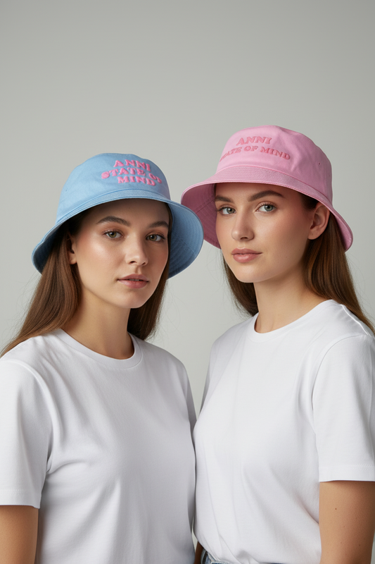 Two girls wearing pastel pink and blue hats with text on a plain background