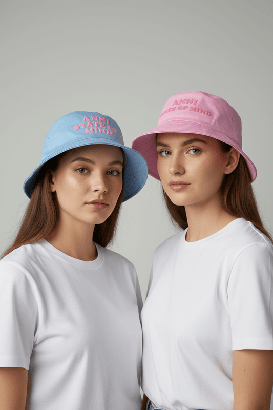 Two girls wearing pastel pink and blue hats with text on a plain background