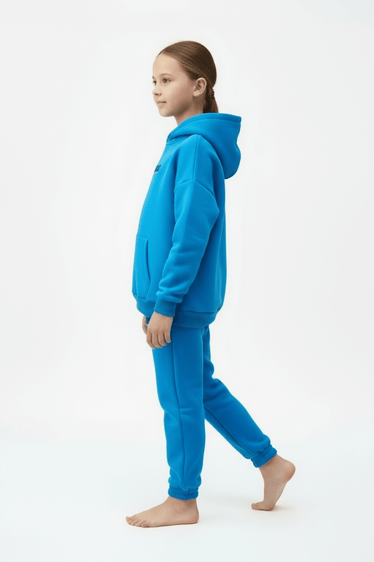 Child wearing a blue hoodie and pants on a white background