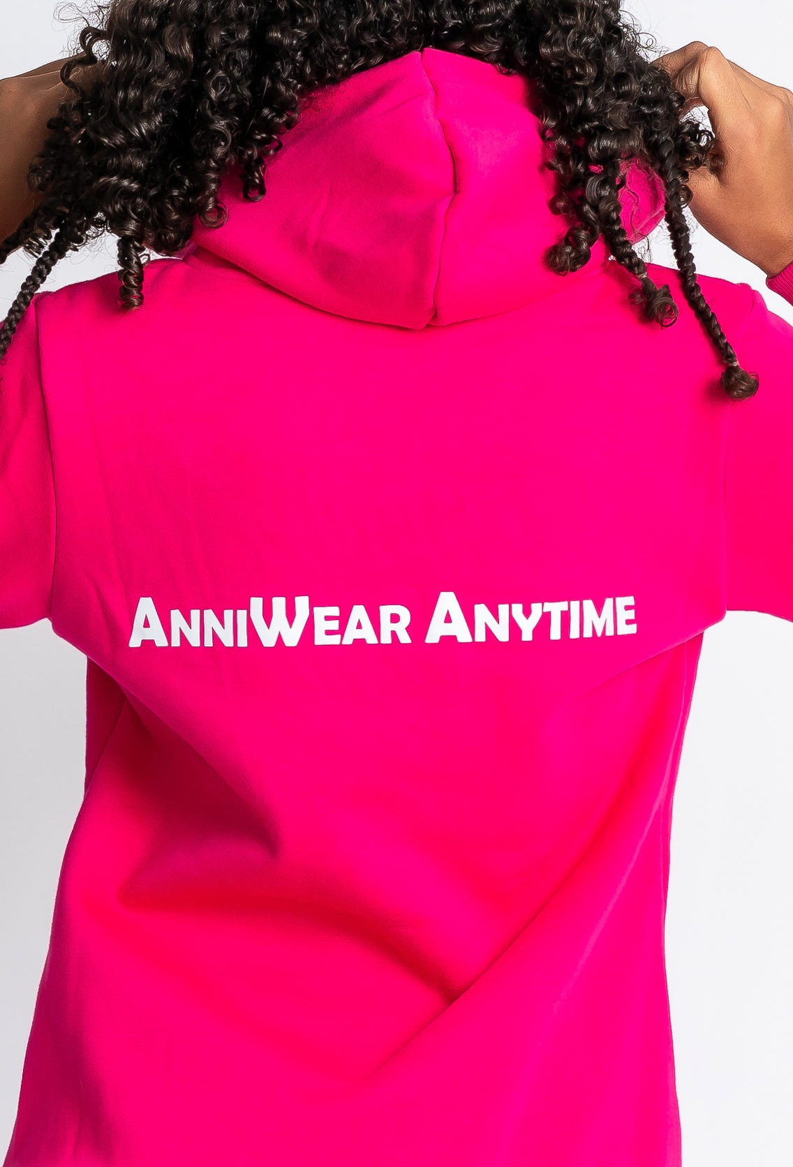 Person wearing a bright pink hoodie with 'AnniWear Anytime' text on the back against a white background