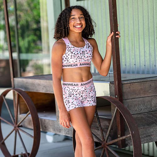 Pink patterned active crop and shorts with 'Anniwear' branding on a white background