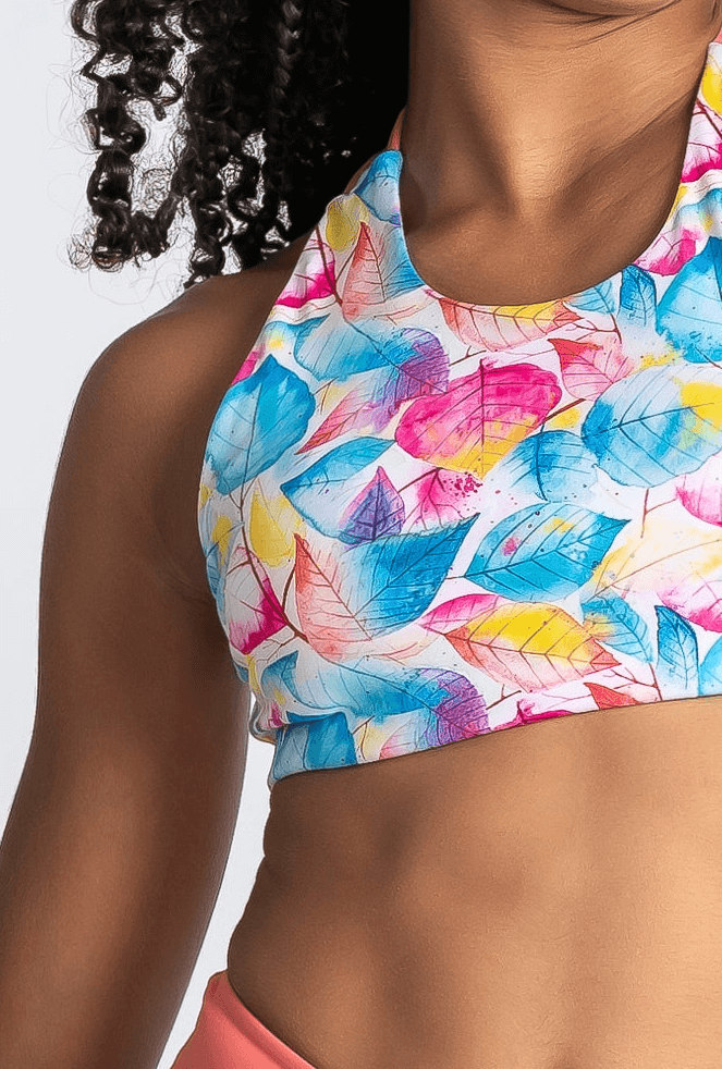 Colorful leaf-patterned gym crop top worn by a person against a neutral background