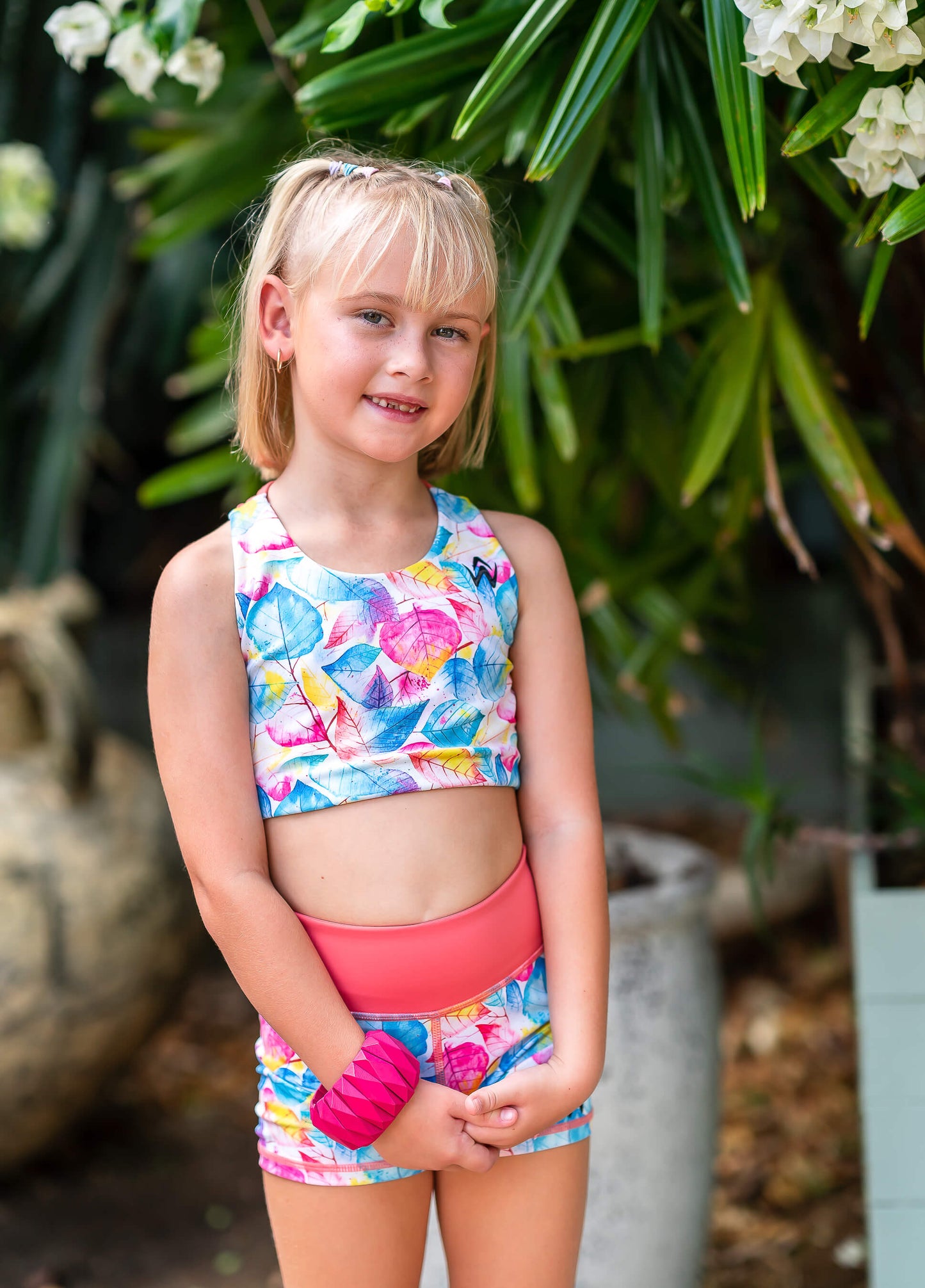 Colorful leaf-patterned crop top and shorts with a brand logo on a white background