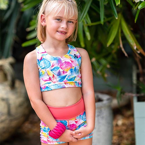 Colorful leaf-patterned crop top and shorts with a brand logo on a white background