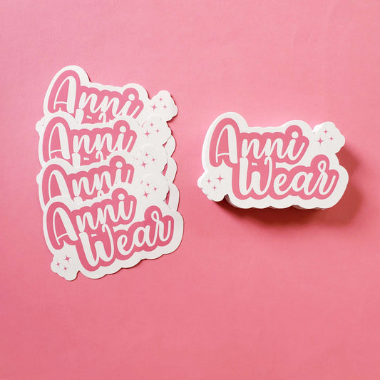 Sticker with 'Anni Wear' text on a pink background