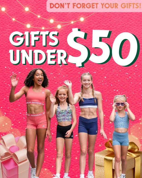 a promotional cover of the gifts under $50 collection with girls wearing colorful activewear on a pink festive background with gifts