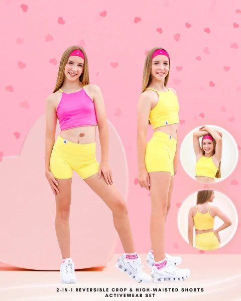 Two models wearing reversible crop top and high-waisted shorts set on a pink background with heart shapes.