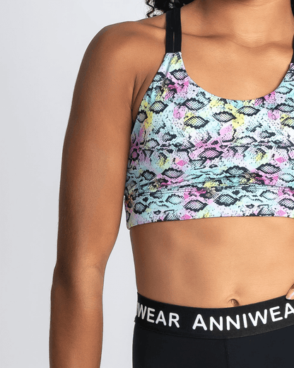 Multicolored patterned sports bra with black waistband displaying 'ANNIWEAR' brand on a plain background.