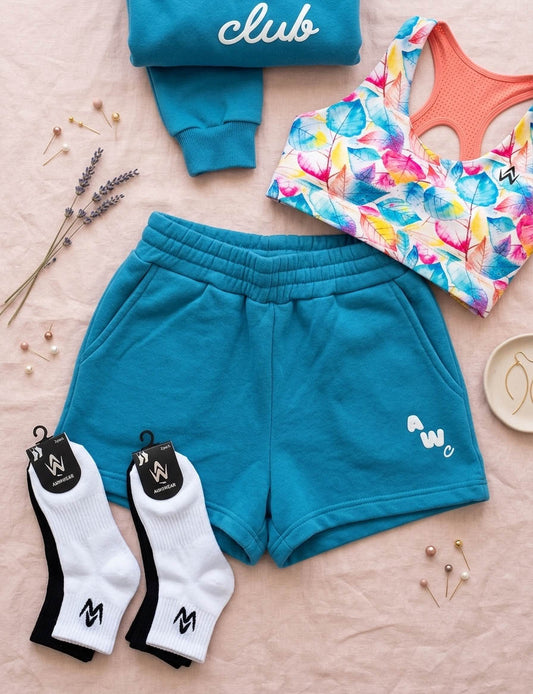 flat lay of sports crop top, shorts, socks on a pink minimalist background