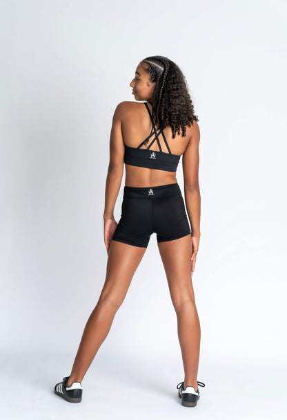 Teen girl wearing black cross over strapped crop and black activewear shorts