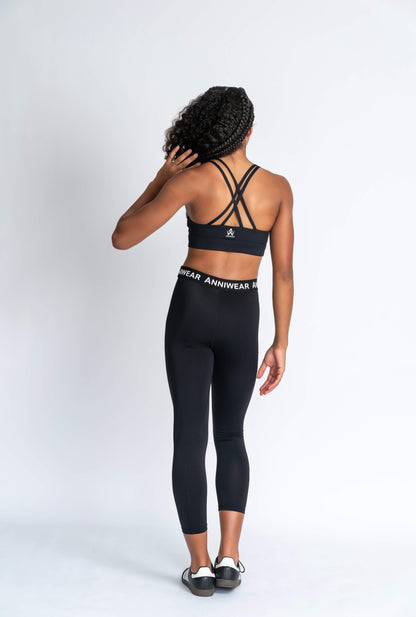 Girl wearing criss cross black strappy crop & black activewear Tights