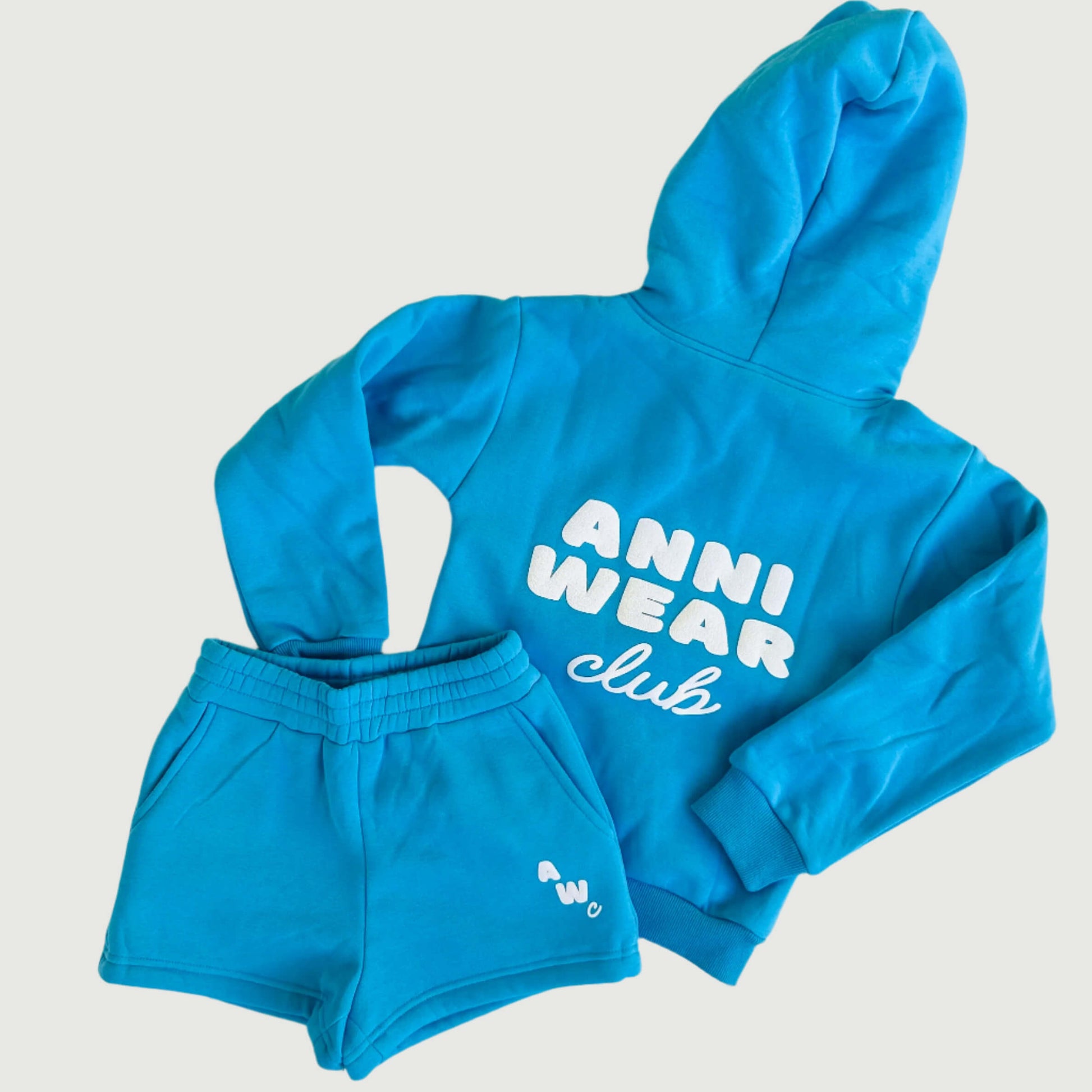 Blue hoodie and shorts set with 'Anni Wear Club' text on a white floor.