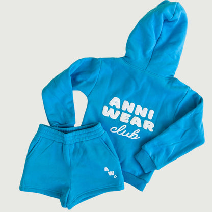 Blue hoodie and shorts set with 'Anni Wear Club' text on a white floor.