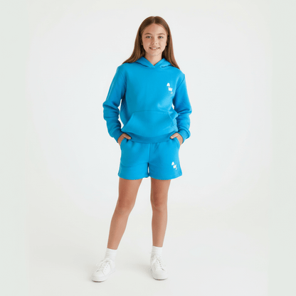 Tween Girl wearing a blue tracksuit short and hoodie set with a logo on a white background