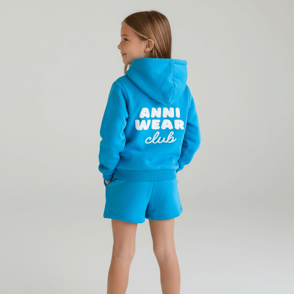 Child wearing a blue hoodie and shorts set with 'Anni Wear Club' text on a plain background