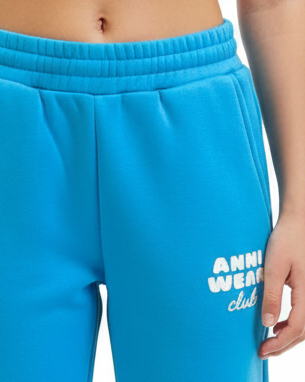 Blue sweatpants with 'ANNA WEAR club' text on a person wearing them.