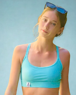 Girl wearing an Aqua sports bra with a small logo on a light blue background