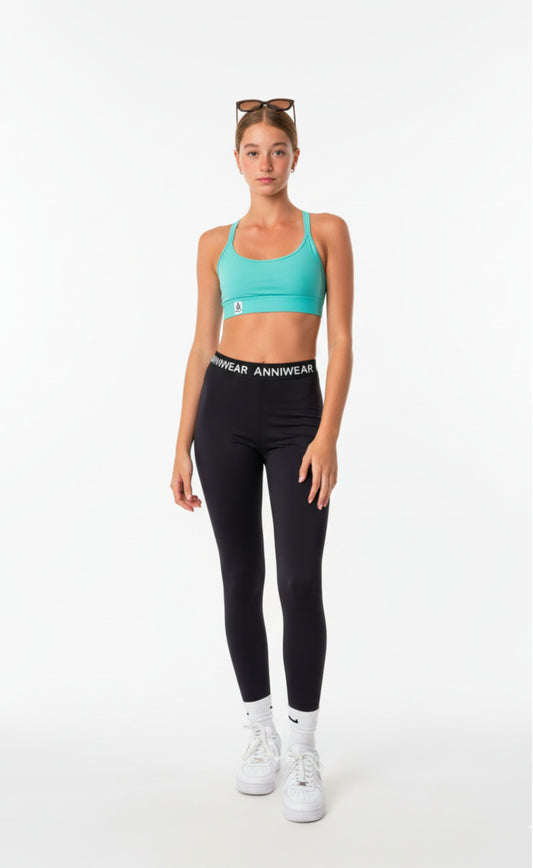 Teen Girl wearing a turquoise sports bra and black leggings with 'Anniwear' branding on a white background