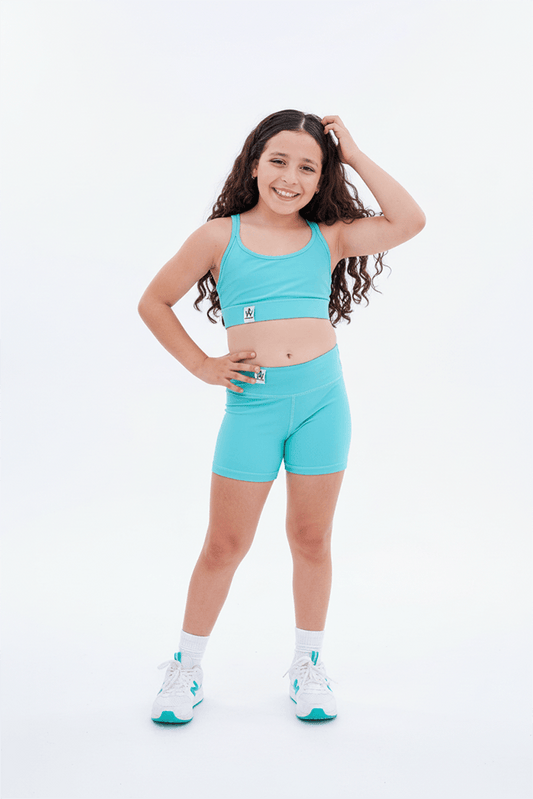 Young girl wearing a turquoise athletic outfit on a white background