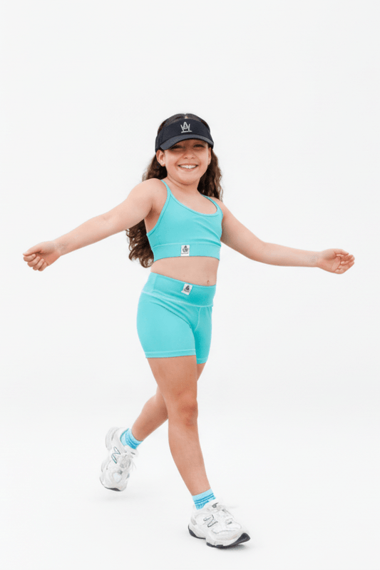 Child wearing a turquoise athletic outfit with a cap on a white background