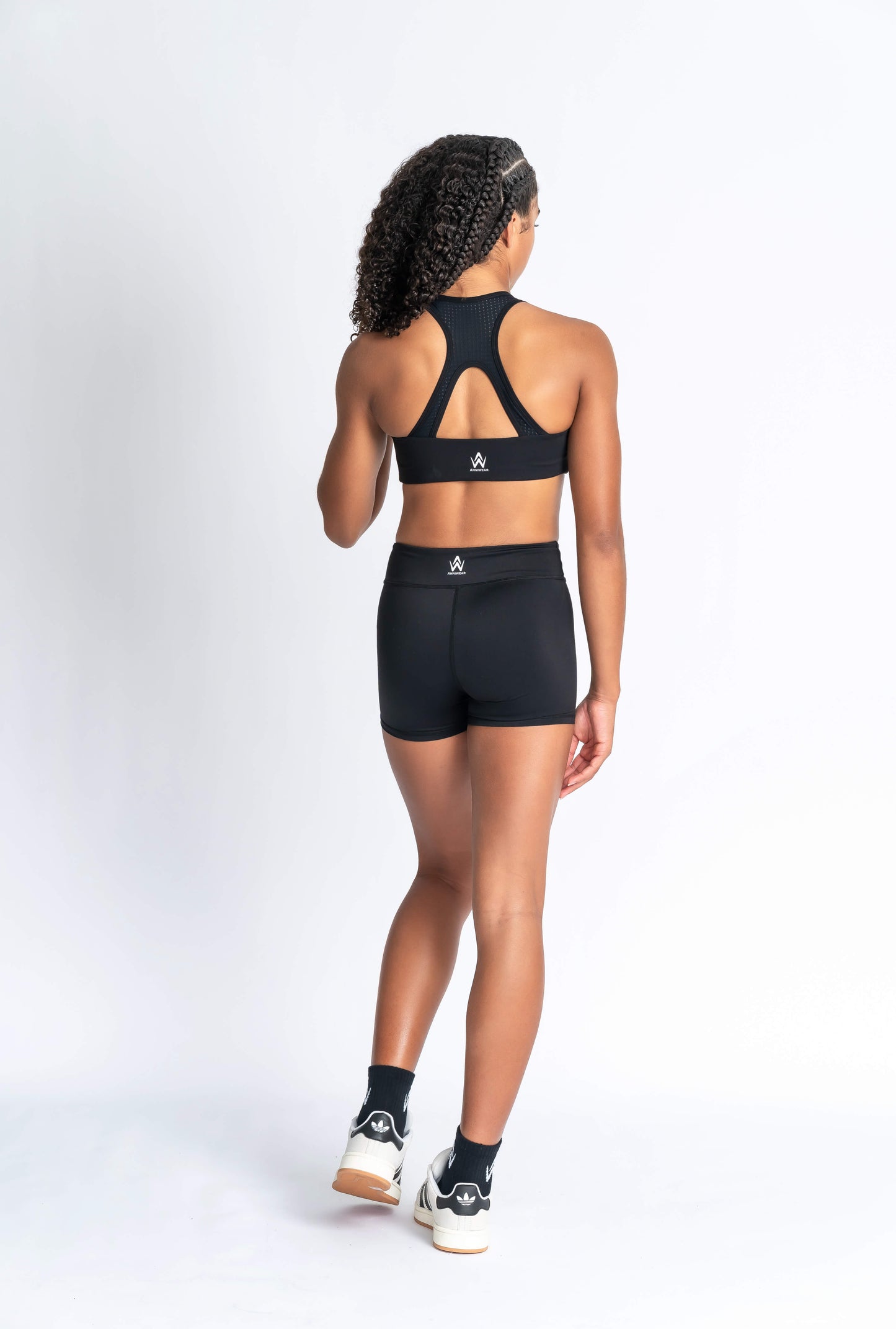 Black sports bra and black shorts with white logo branding