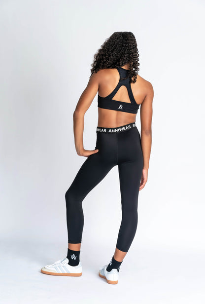 Black sports bra and leggings with 'Anniwear' branding on a plain background