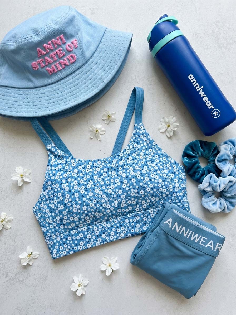 Blue athletic outfit with floral sports bra, cap, leggings, and water bottle on a light background.