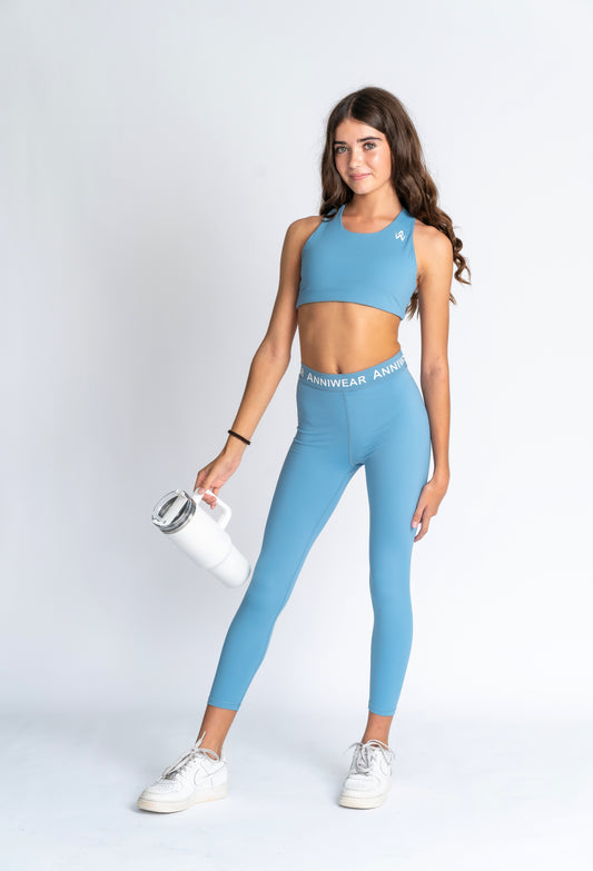Blue sports bra and leggings with brand logo on a white background