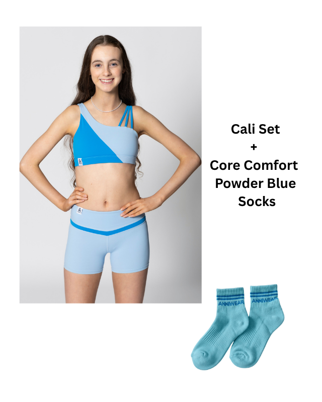 Woman wearing a blue sports bra and shorts set with matching socks on a white background