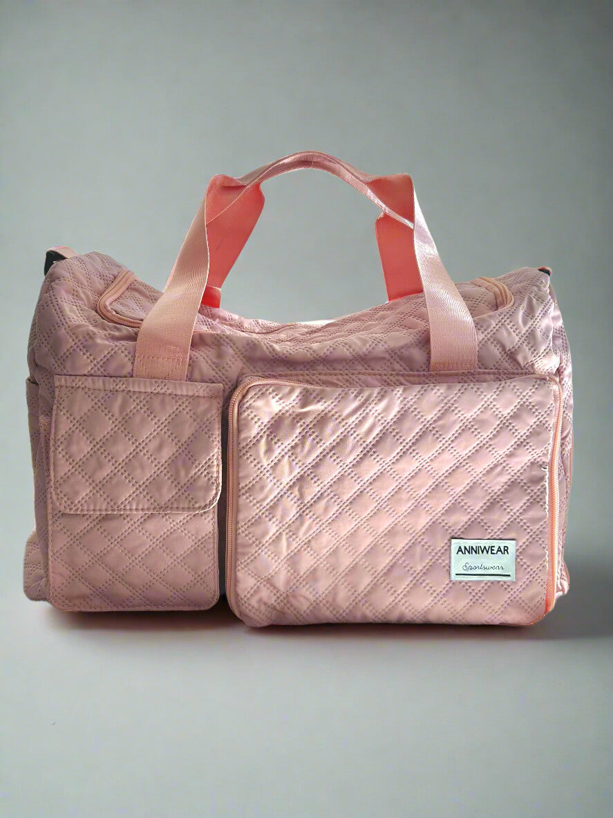 Pink duffel bag with a visible brand label on a bed