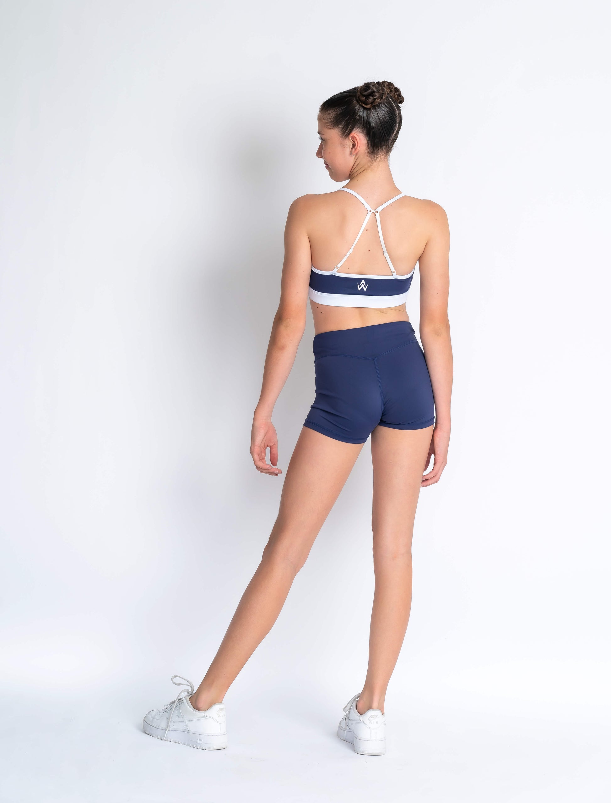 Navy blue & white sports crop and navy blue high-waisted shorts on a plain background