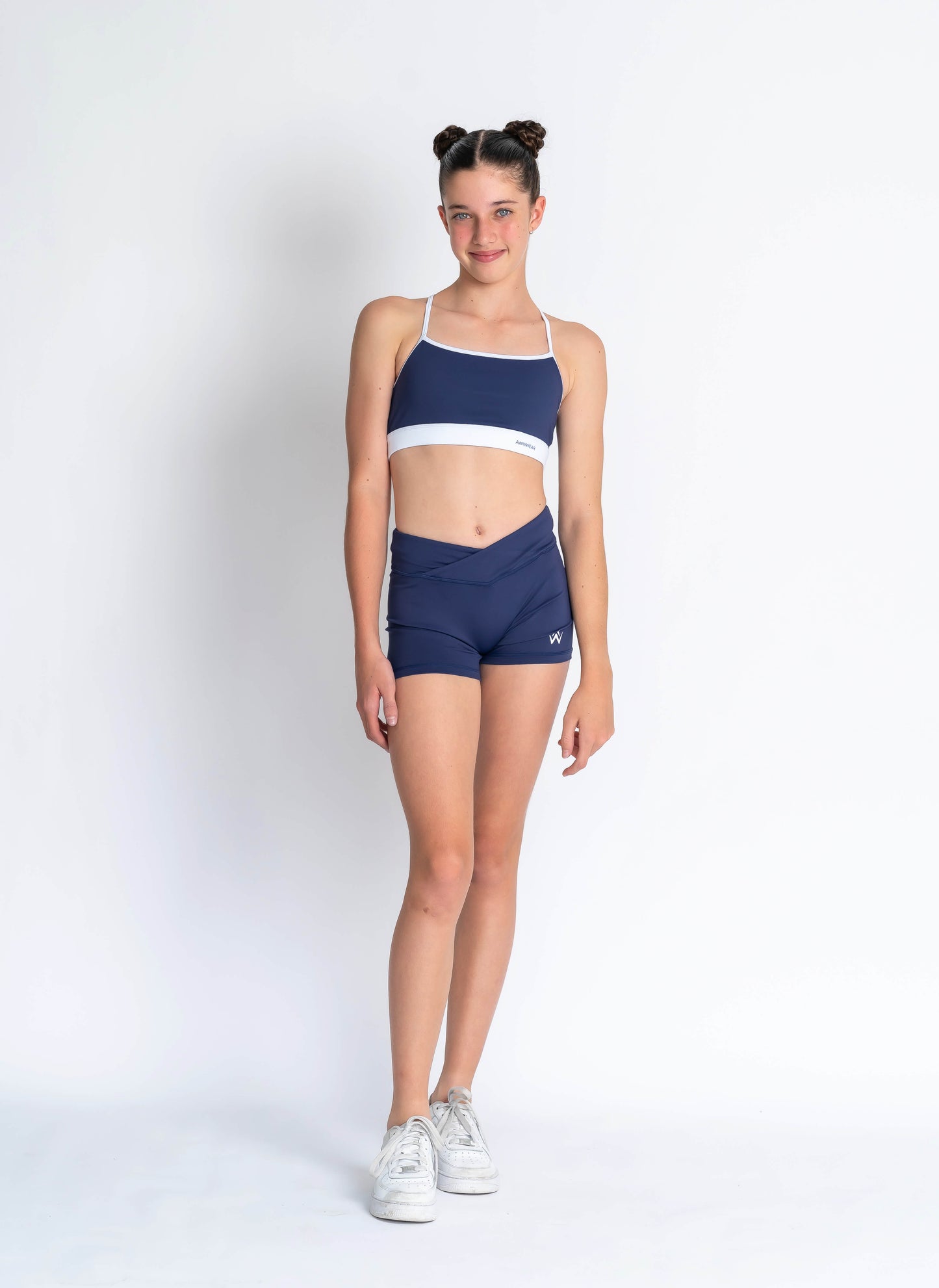 Navy blue & white sports crop and navy blue high-waisted shorts on a plain background