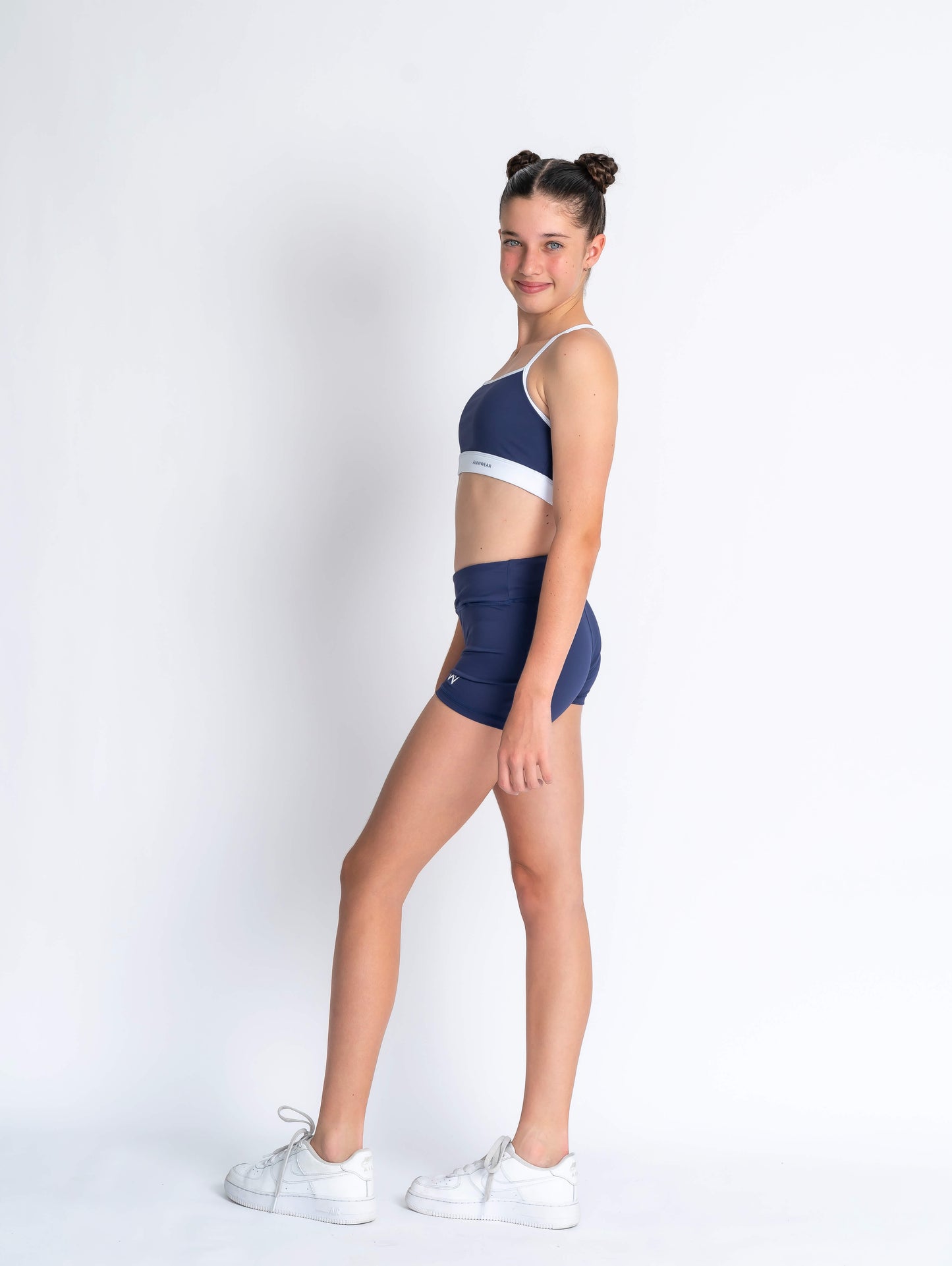 Navy blue & white sports crop and navy blue high-waisted shorts on a plain background