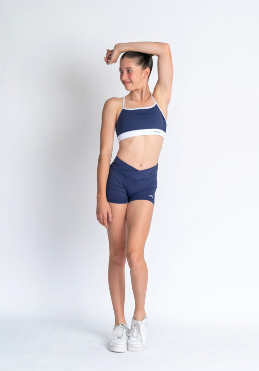 Navy and white sports bra and Navy shorts with a logo on a plain background