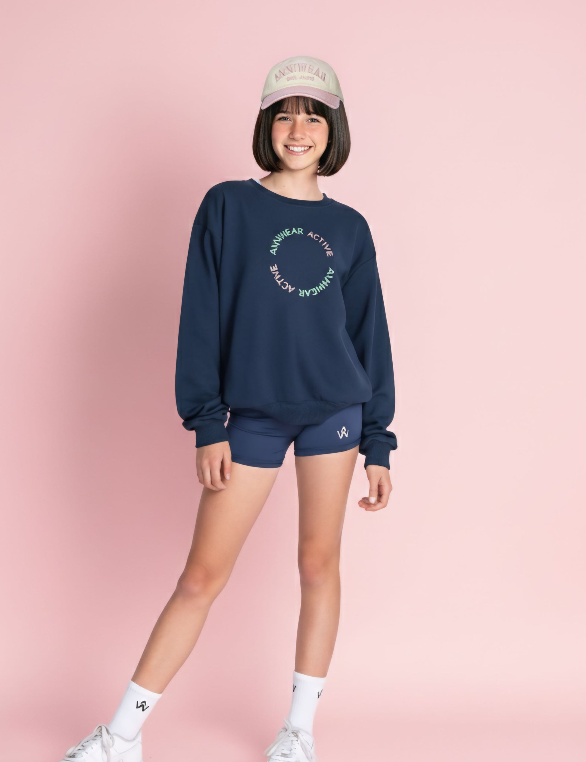 Person wearing a navy sweatshirt and shorts set with a pink background