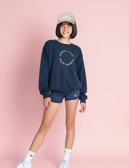 Person wearing a navy sweatshirt and shorts set with a pink background