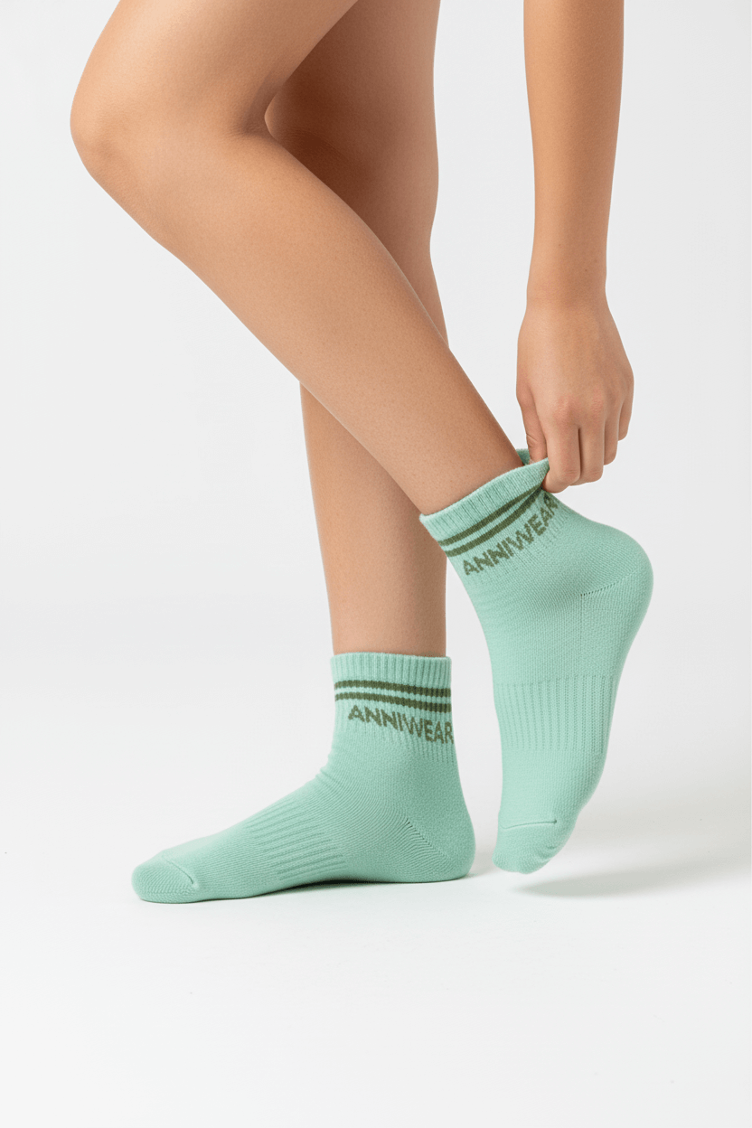 Person wearing light green socks with 'ANNIWEAR' branding on a white background