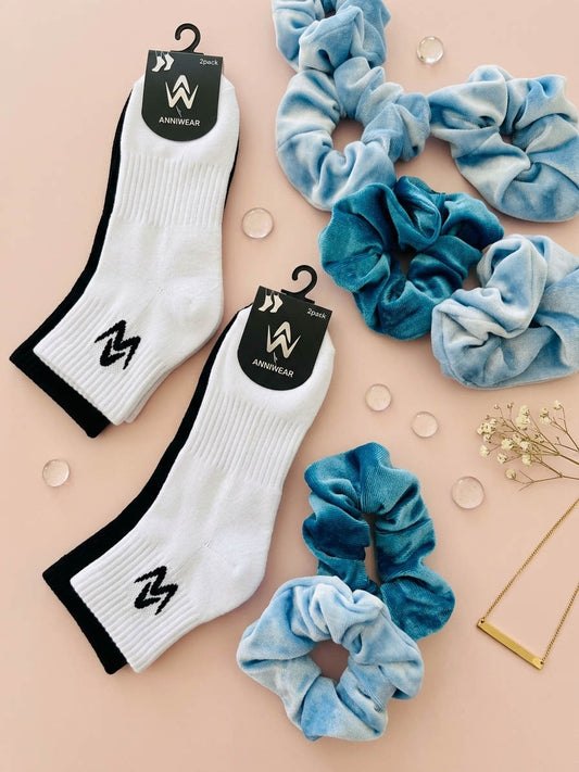 White socks with black logo and blue scrunchies on a beige background