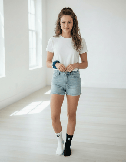 Woman wearing a white t-shirt, light blue denim shorts, and black and white socks in a bright room.