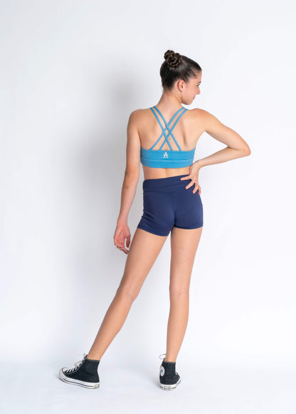 Blue sports bra with criss-cross straps and navy sport shorts on a plain background