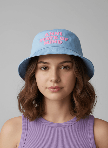 Person wearing a blue bucket hat with pink text on a gray background