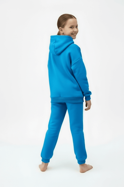 Child wearing a blue hoodie and pants on a white background